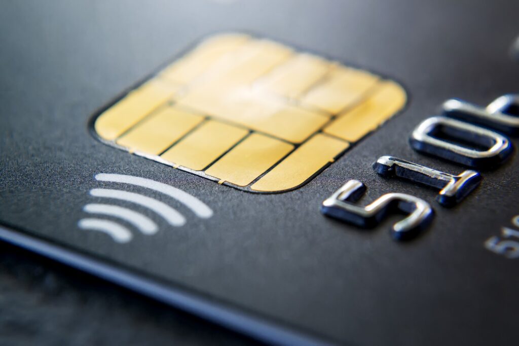 Black credit card with a gold EMV chip and contactless payment symbol